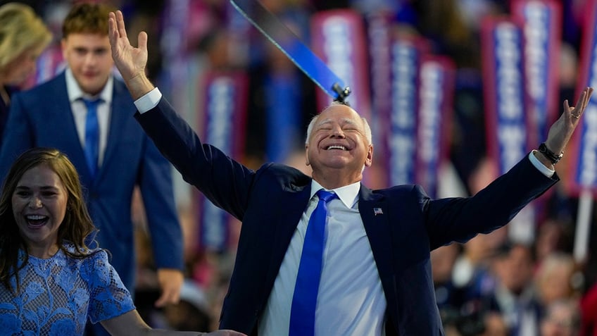 Tim Walz arms upward, eyes closed happy at DNC 