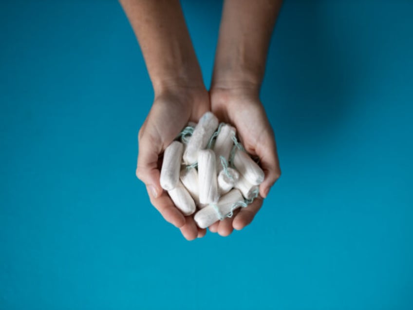 ADDED ON 8-8-24 -- Close-up of hands holding tampons against blue background - stock photo