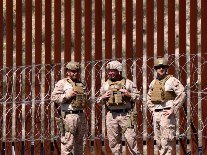 Members of the U.S. military stand in front of the border wall along the U.S. and Mexico b