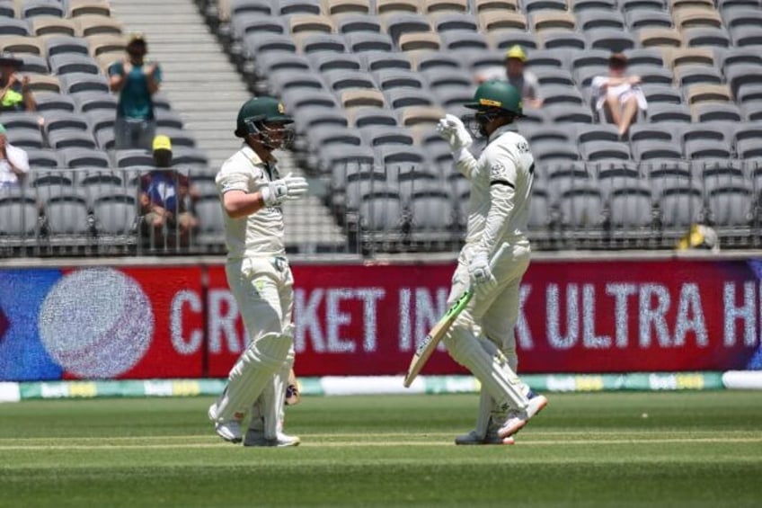 Australia’s David Warner (L) celebrates after scoring a half-century (50 runs) with teammate Usman Khawaja