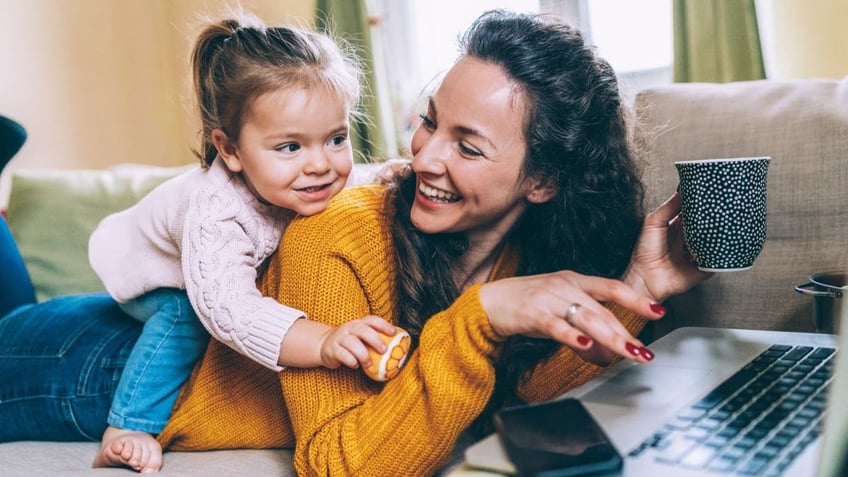 Laughing mom showing baby girl computer