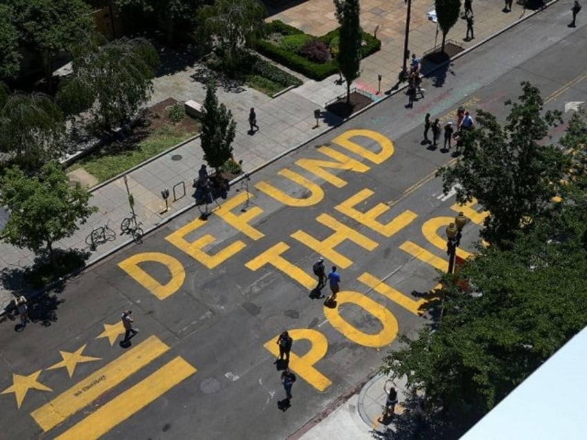 People walk down 16th street after “Defund The Police” was painted on the street near the White House on June 08, 2020 in Washington, DC. After days of protests in DC over the death of George Floyd, DC Mayor Muriel Bowser renamed that section of 16th street "Black Lives Matter …