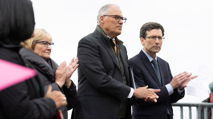 Washington Gov. Jay Inslee stands next to Attorney General Bob Ferguson