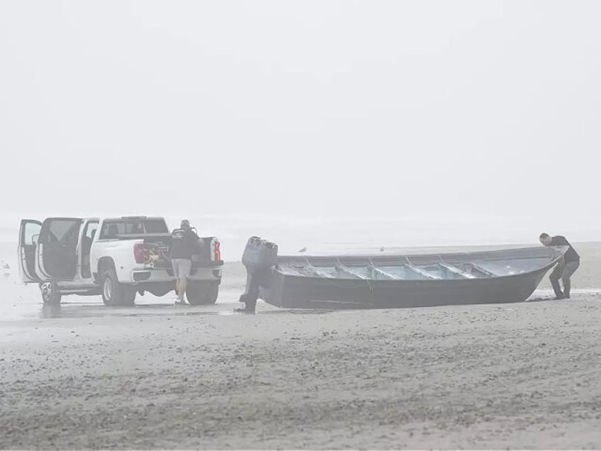 FILE - Boat salvager Robert Butler, left, and KC Ivers, right, prepare to move one of two boats that capsized in shallow but turbulent surf off the San Diego coast, on Blacks Beach, March 12, 2023. At least seven of eight people killed when the two boats capsized were Mexican …