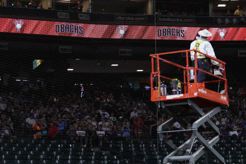 Beekeeper Matt Hilton removes a colony of bees that formed on the net behind home plate during a delay to the MLB game between the Los Angeles...