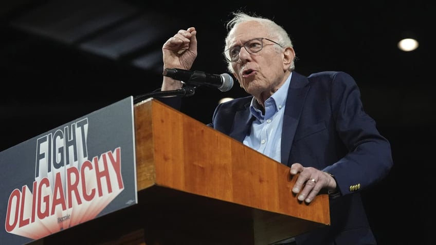 Bernie Sanders speaks at a podium with a sign that reads, "Fight Oligarchy"