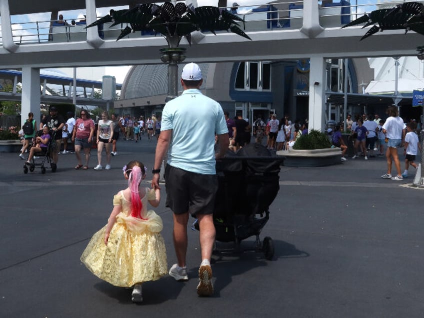 ORLANDO, FL - MAY 31: A man walks with his daughter towards Space Mountain at the Magic Ki