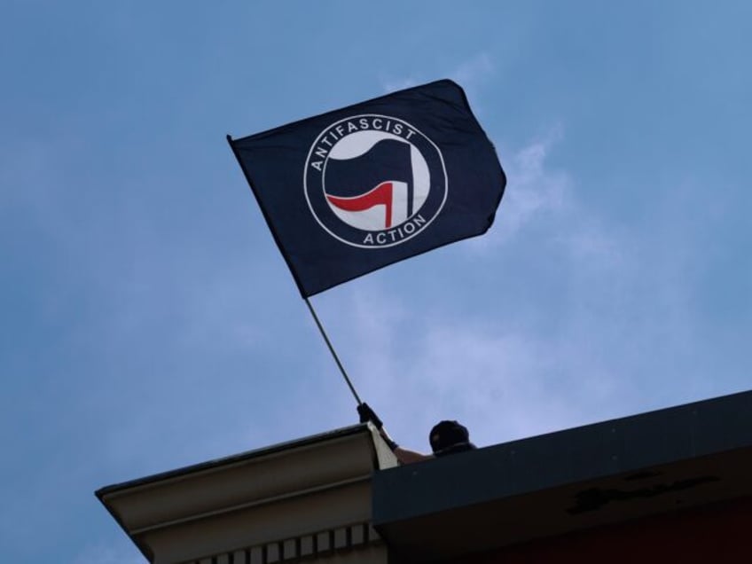 01 May 2024, Hamburg: A masked man waves an anti-fascist flag during a demonstration by le