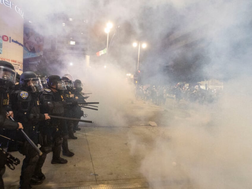 Police officers in riot clash with demonstrators during a protest following federal immigr