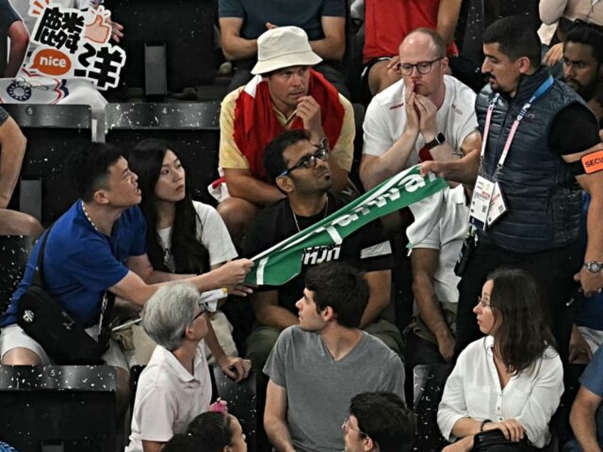 A security member removes a banner showing the name "Taiwan" from a fan in the audience du