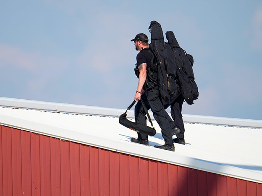 Police snipers walk on a roof to set up before Republican presidential candidate former President Donald Trump speaks at a campaign event in Butler, Pa., on Saturday, July 13, 2023. (AP Photo/Gene J. Puskar)