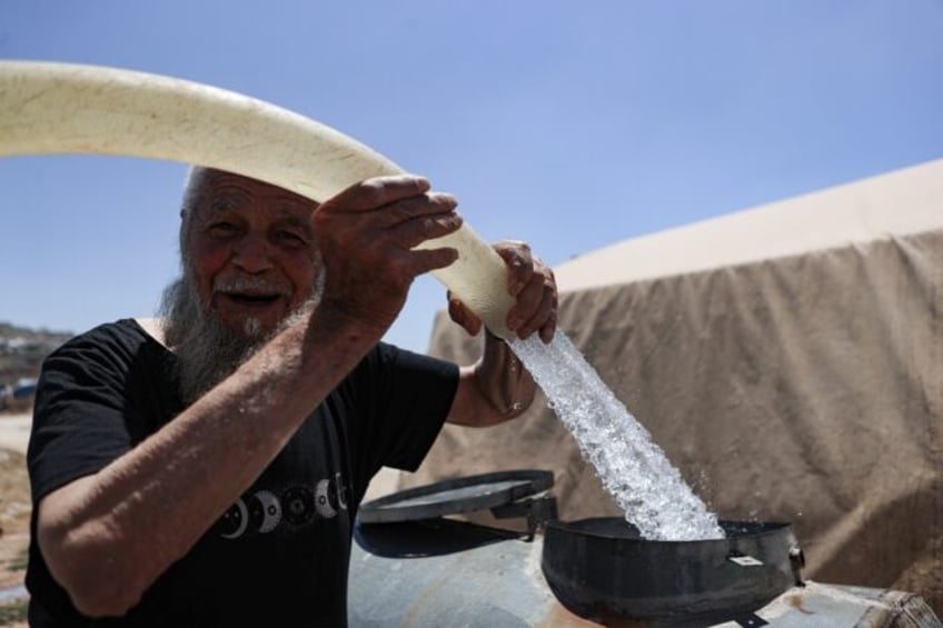 A man fills barrels with water at a camp for internally displaced people in northern Syria