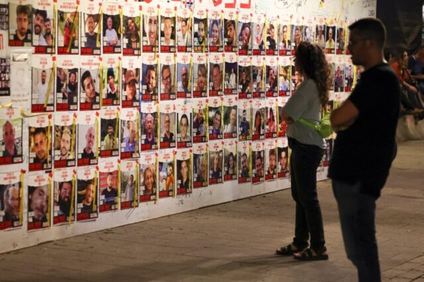 Israelis look at portraits of hostages, held in Gaza since the October 7 attack, posted on