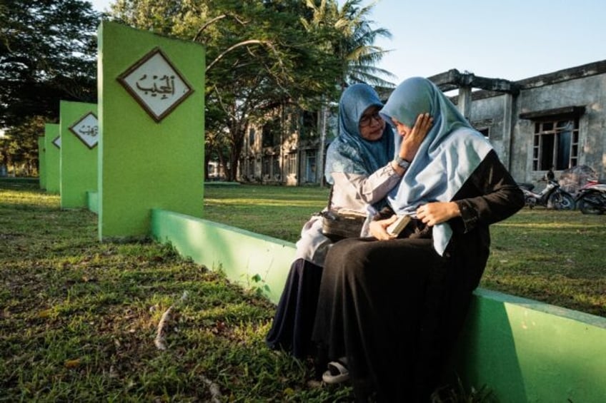 A woman comforts her daughter after prayers at a mass grave in Indonesia's Aceh