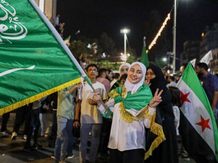 A girl holds a Saudi flag in Homs, Syria, Tuesday, May 13, 2025, as she celebrates U.S. Pr