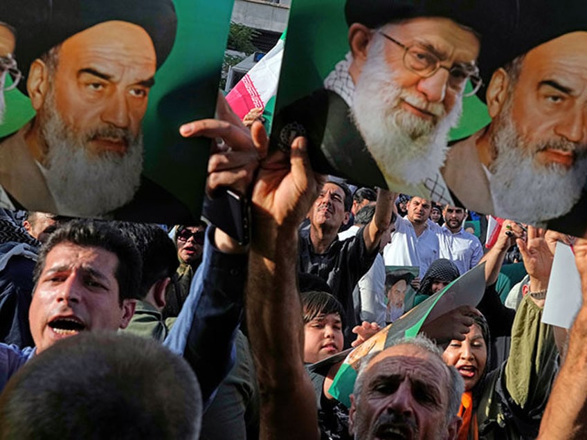 Iranian protesters hold up posters showing the Supreme Leader Ayatollah Ali Khamenei, cent