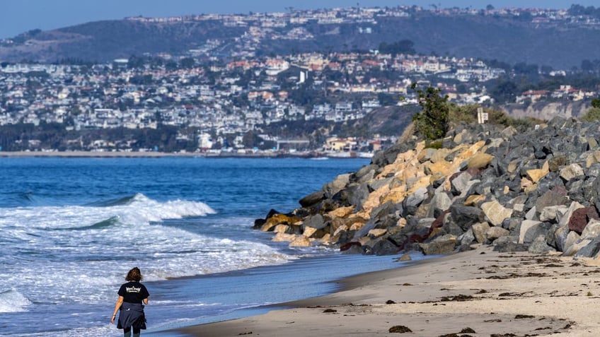 A woman walks on the beach in San Clemente