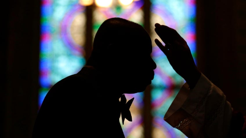 A churchgoer prepares to receive ashes from an Archbishop