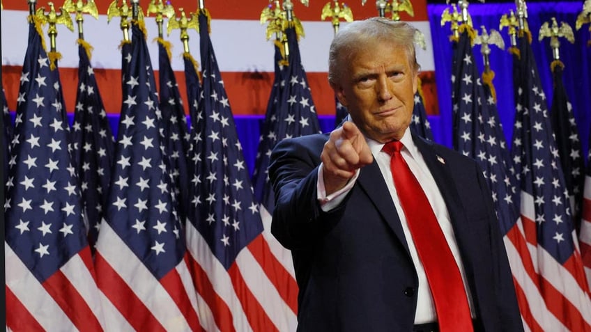 Donald Trump pointing with US flags behind them