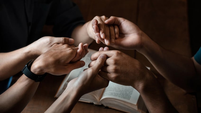 people clasping hands, praying