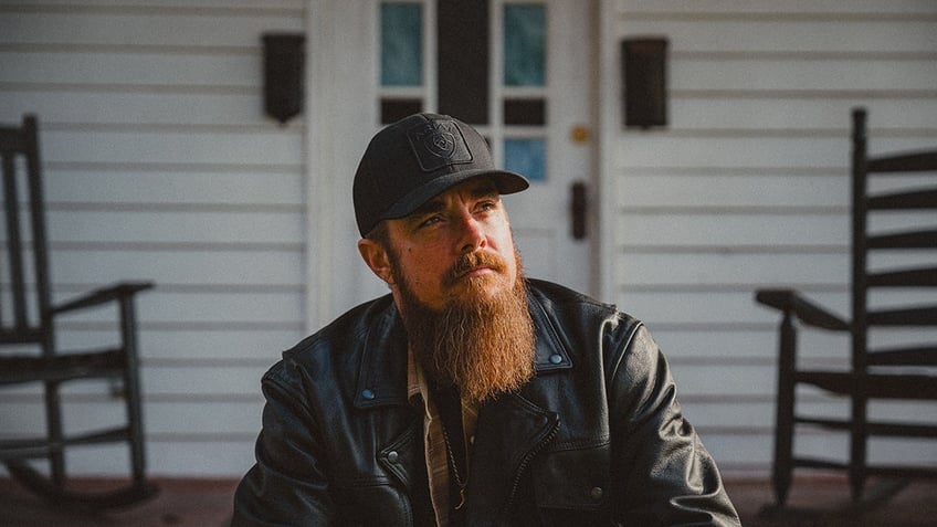 A close-up of Whey Jennings sitting in front of a white house