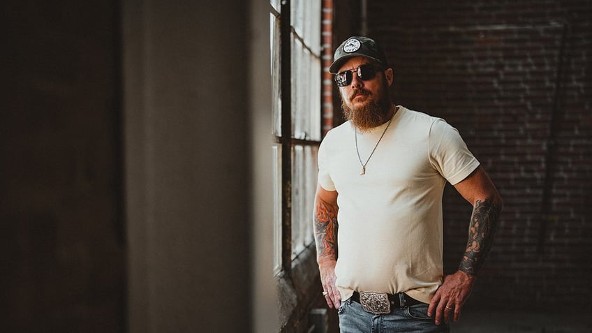 Whey Jennings wearing a white shirt, jeans and a hat with sunglasses