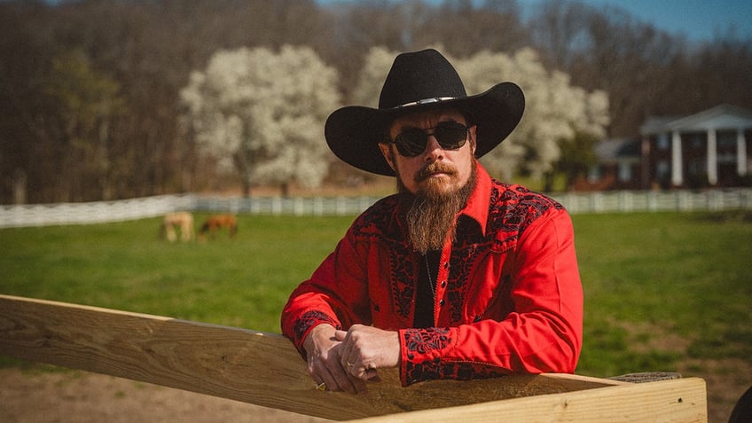 Whey Jennings wearing a red shirt and sitting in front of a park