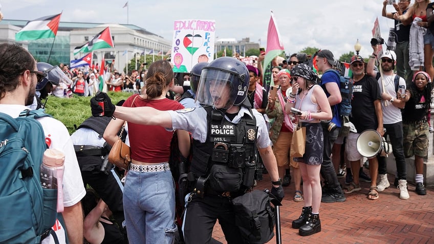 cop in riot gear with pepper spray confronts protester