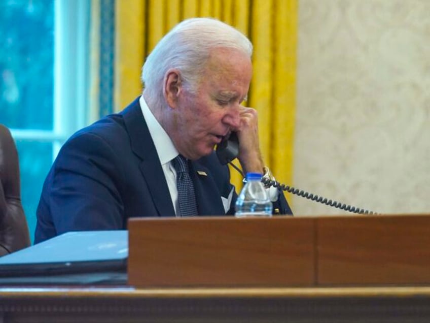 In this image made through a window, President Joe Biden talks on the phone with Ukrainian