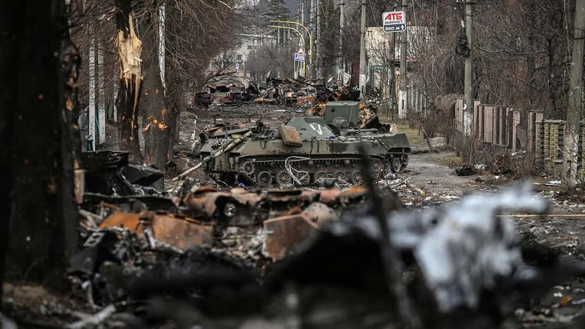 A tank sits in the middle of a destroyed road.