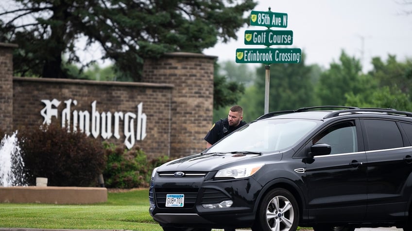 A police officer standing next to a car in front of a street sign