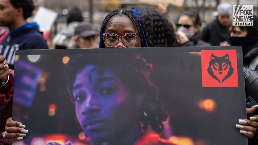 Individuals hold protest signs as they await Daniel Penny’s arrival outside of the Manhattan Criminal Courthouse