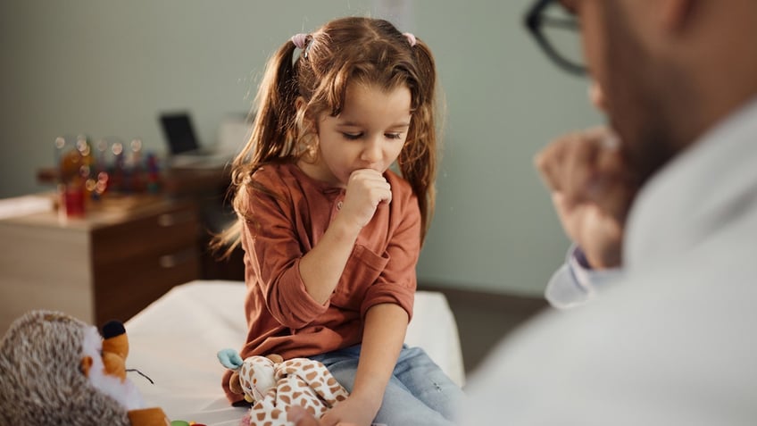 Girl coughing at doctor