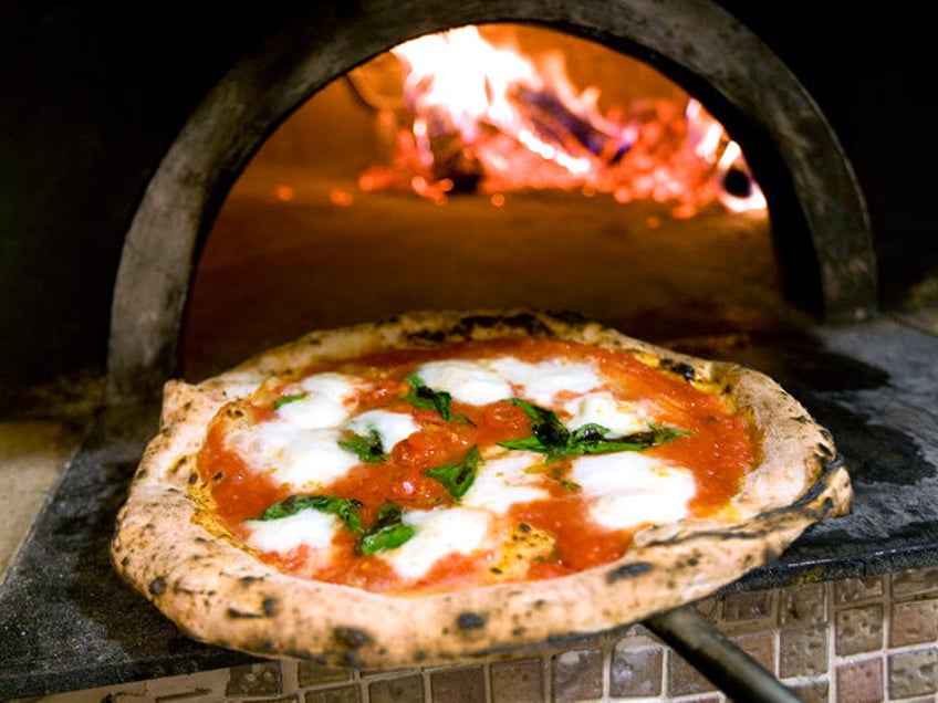 UNITED STATES - JUNE 02: Roberto Caporuscio holds a margherita pizza in front of the wood