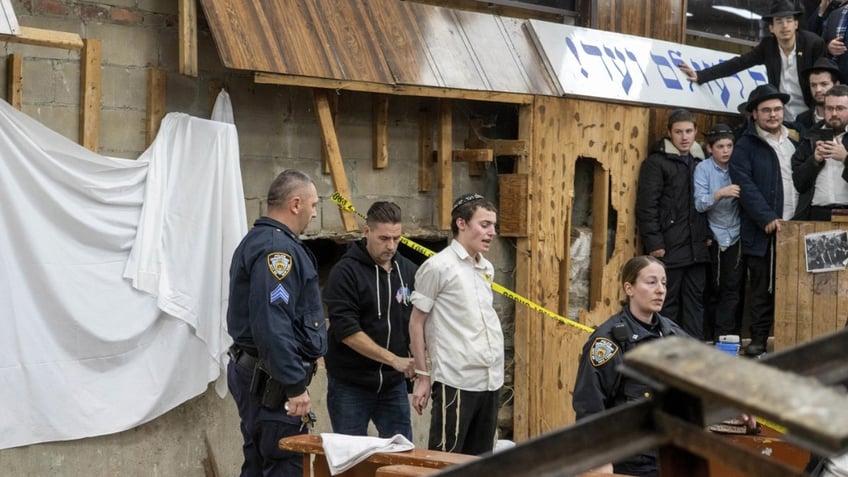 NYPD officers arrest a students after he was removed from a breach in the wall of the synagogue that led to a tunnel dug by students.