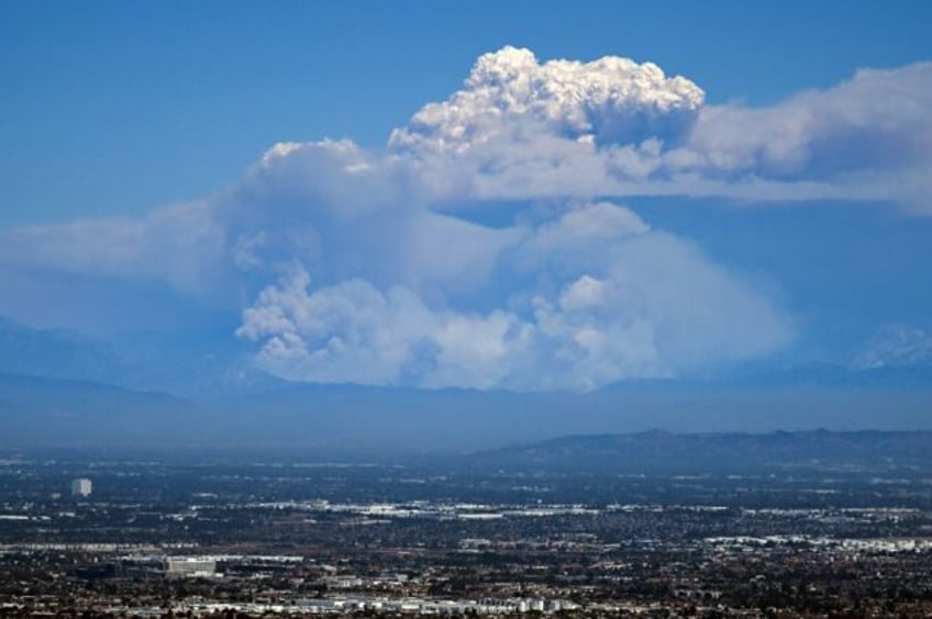 Thick columns of smoke rise above parts of Los Angeles from one of the three wildfires bur