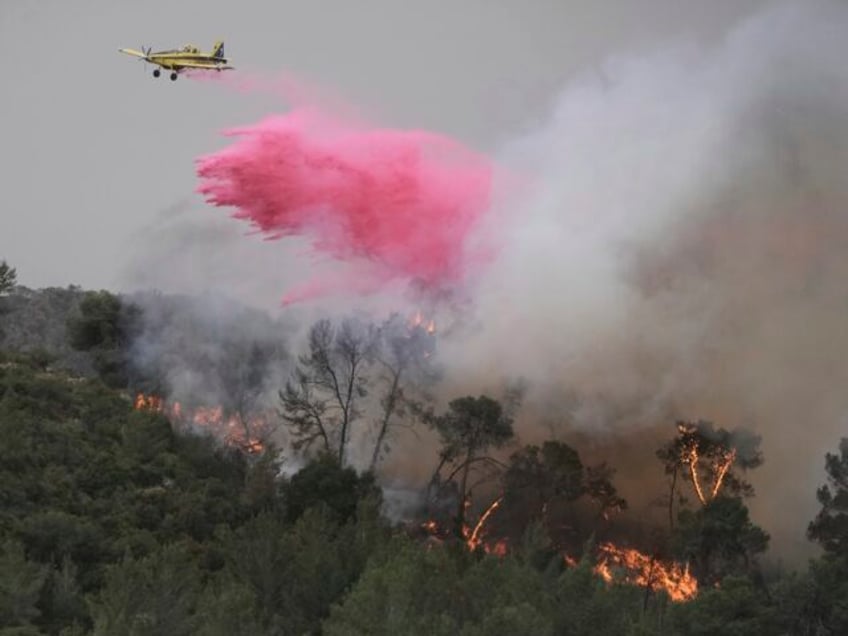A plane uses a fire retardant to extinguish a fire burning in a forest near Jerusalem, Wed