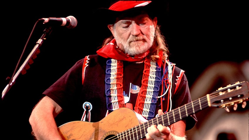 Willie Nelson playing his guitar, Trigger, on stage