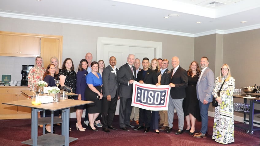 Wilmer Valderrama with a group of people holding a USO sign.