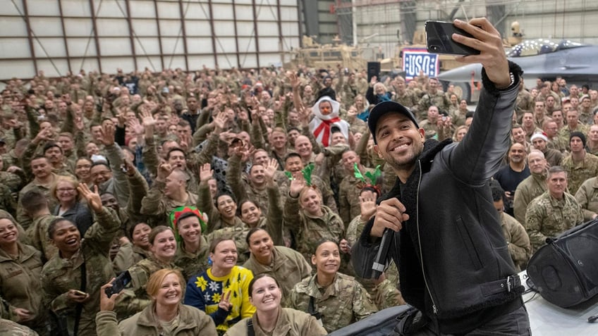 Wilmer Valderrama taking a selfie with a group of soldiers.