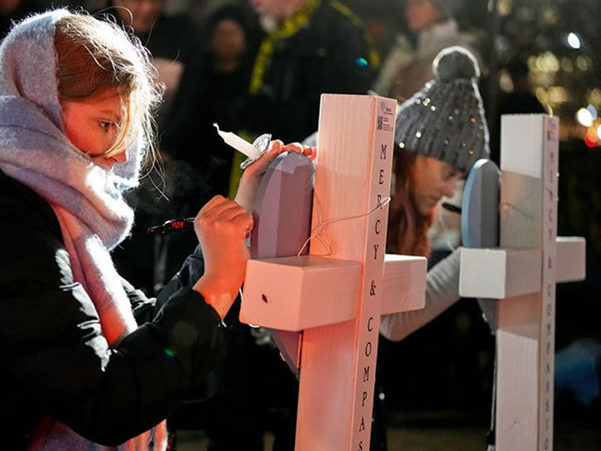 Supporters sign crosses during a candlelight vigil Tuesday, Dec. 17, 2024, outside the Wis