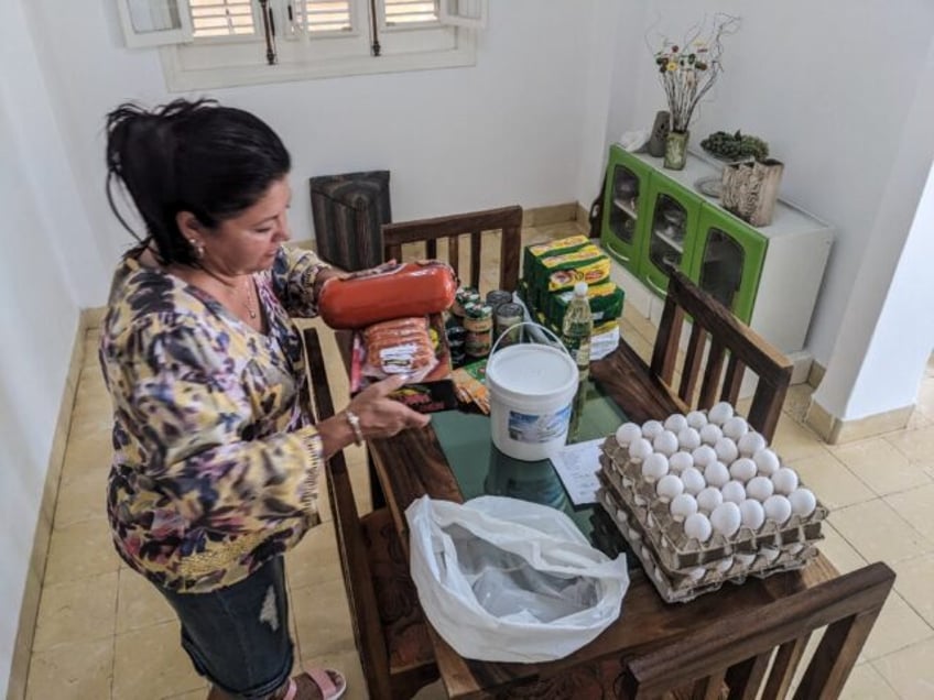 Maria Paez unpacks a box of food items sent from her children in Miami to Havana