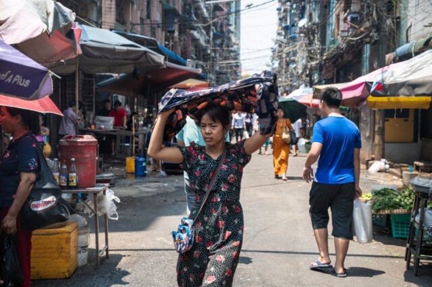 A woman shields herself from the sun as she walks along a Yangon street on a hot day last