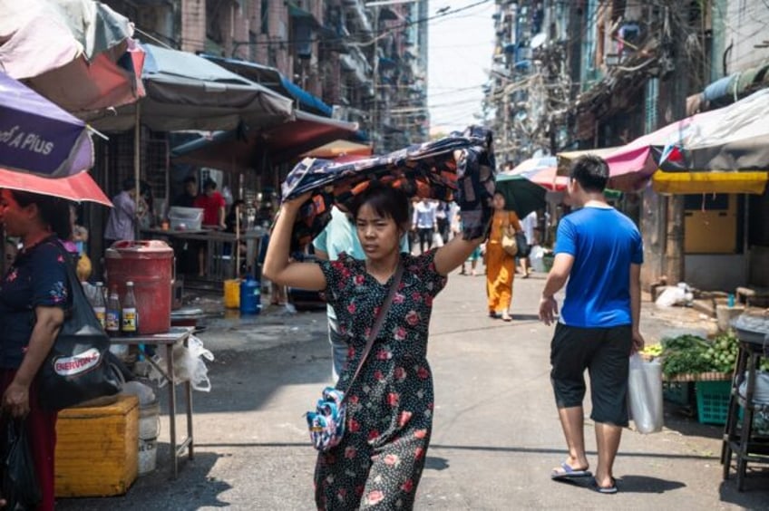 A woman shields herself from the sun as she walks along a Yangon street on a hot day last