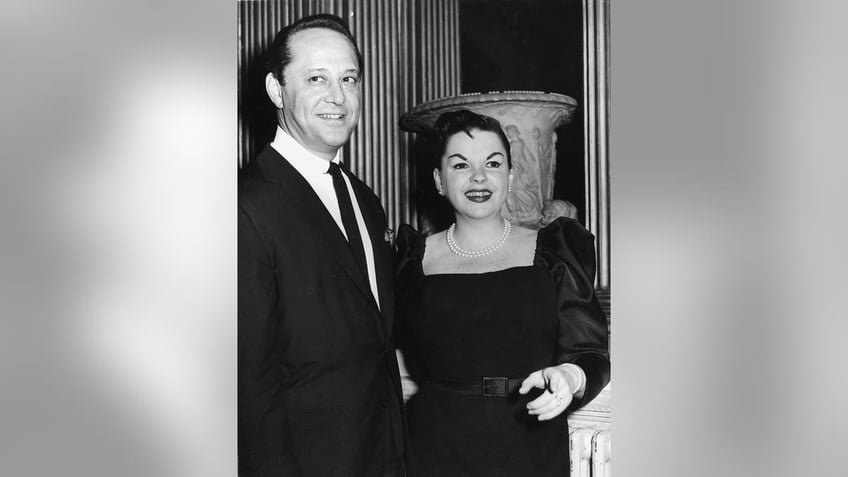 Sid Luft smiling next to Judy Garland in a black dress