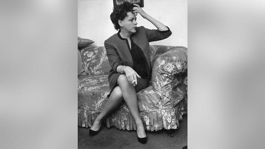 Judy Garland sitting on a couch and stroking her hair