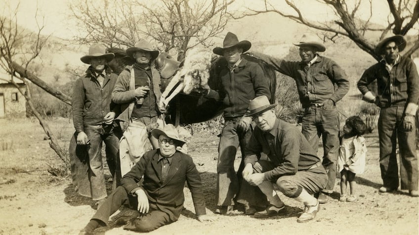 Cowboys with dead wolf slung over horse