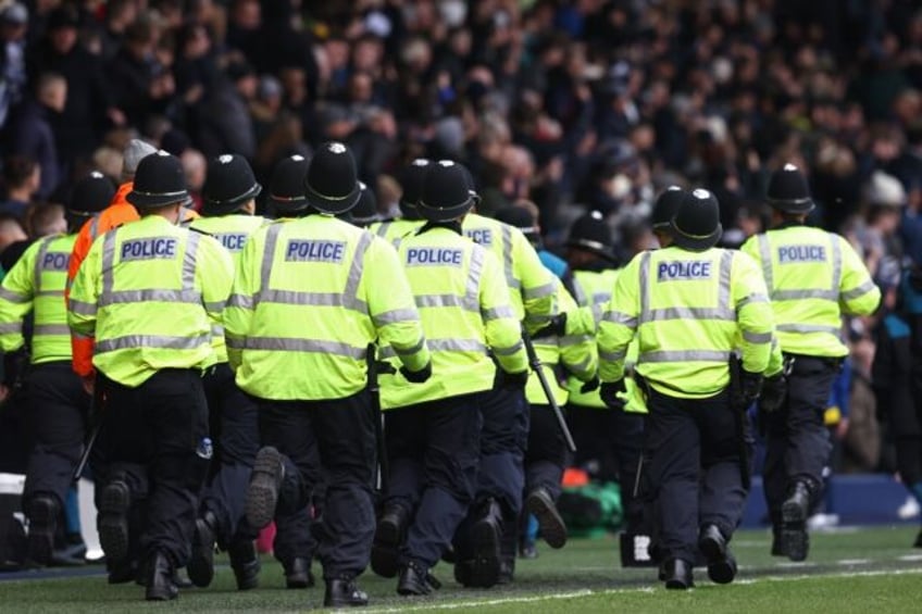 Police officers run to reinforce colleagues after trouble brokes out between fans West Bromwich Albion and Wolverhampton Wanderers fans