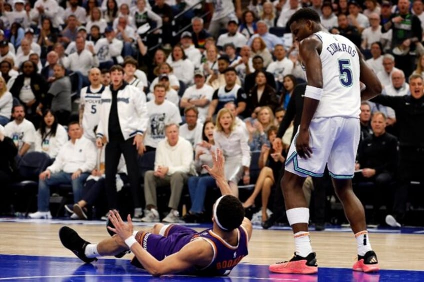 Minnesota's Anthony Edwards looks down at Phoenix's Devin Booker during the Timberwolves v