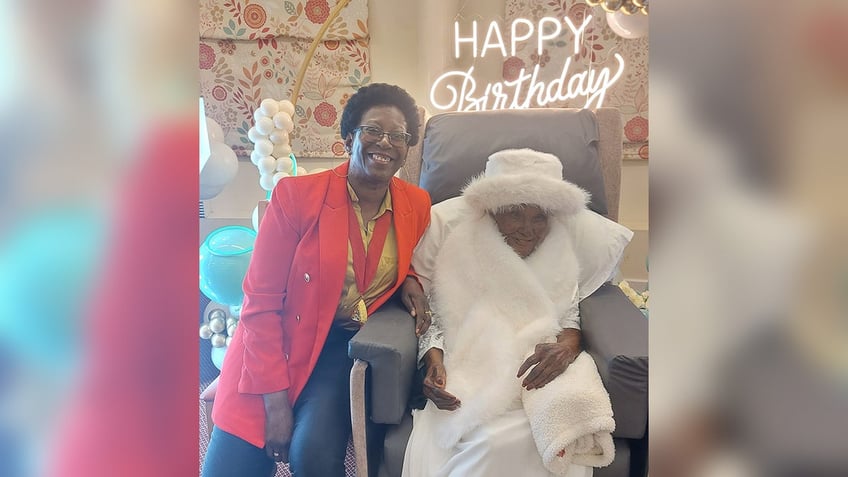 107-year-old great-great-great grandmother Mary Thomas sits next to a family member at her birthday celebration.